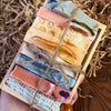 Assorted colorful soap bars in a wooden holder on a rustic background